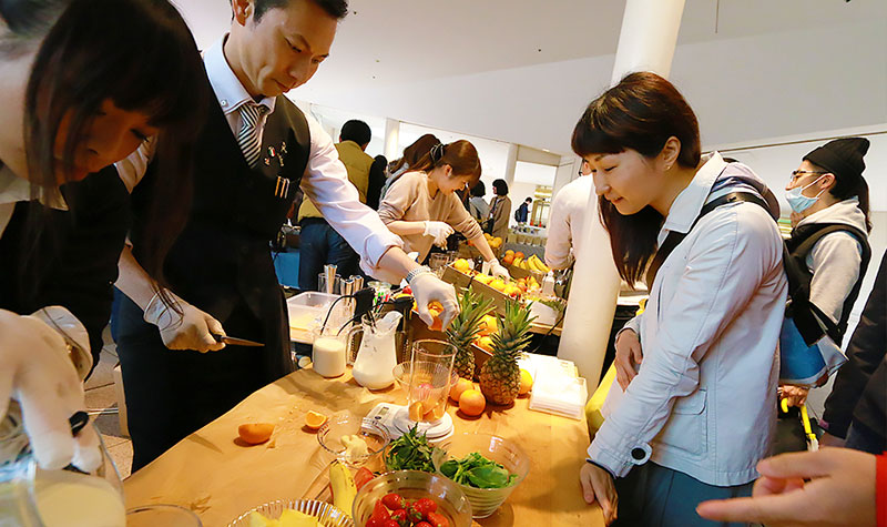 “まるごと”に驚きながらスムージーができるのを見る女性