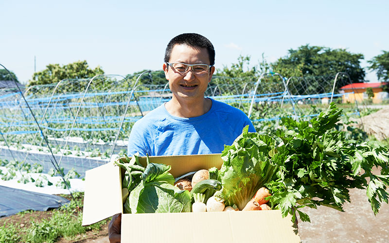 発送する野菜箱を持つ久松さん
