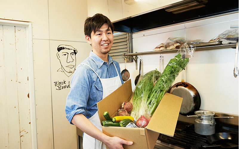 久松農園の野菜を手にする店長の大江さん