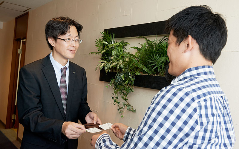 笑顔で名刺交換するMさんと熊原さん