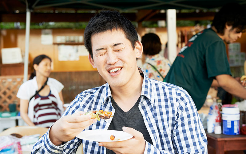 何やらおいしそうな食べ物を手に満足げな笑顔のMさん!