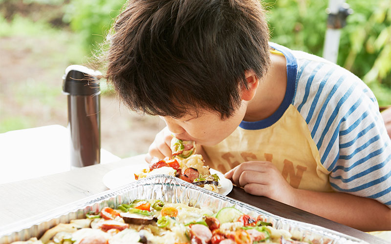あつあつピザを口にいれる子供。ピザに夢中!