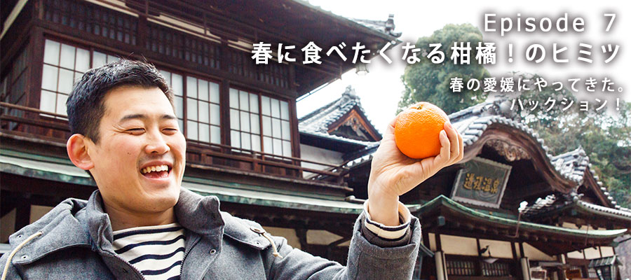 愛媛・道後温泉前でみかんを掲げる写真