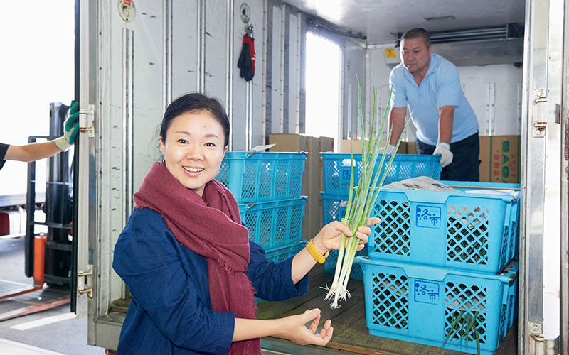 保冷車でやって来た野菜を持つ笑顔のふじわらさん