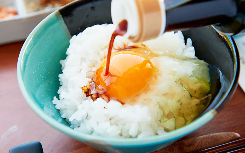 白飯に生卵をのせ、そこに特製の専用醤油(天のしずく)をかける様子