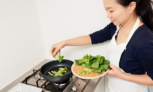 小松菜の茎をフライパンに入れる様子